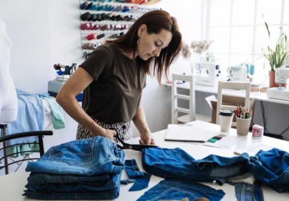 A person cutting jeans on a table AI-generated content may be incorrect.